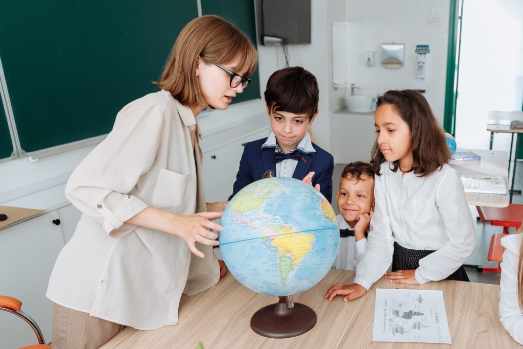 a teacher is using globe to teacher students, it is one of the important form of teaching aid where indulgement of teacher and students are equal.